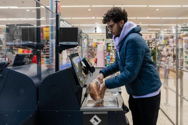 Side view of a man scanning items in a supermarket.